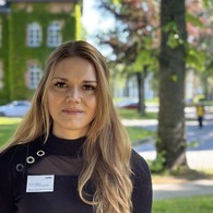 Denise Kolleck schaut in die Kamera, im Hintergrund grüne Büsche Denise Kolleck schaut in die Kamera, im Hintergrund grüne Büsche