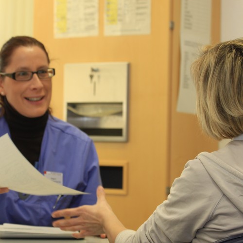 Eine Krankenschwester reicht einer Patientin ein Aufnahmeformular