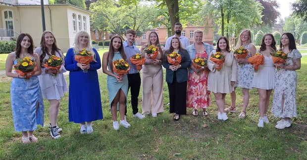 Pflegeschülerinnen und Pflegeschüler mit ihren Zeugnissen im Garten vor der Akademie.