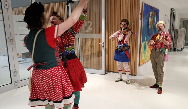 Zwei Clowns tanzen im Flur der Station, zwei weitere betrachten das Ganze.